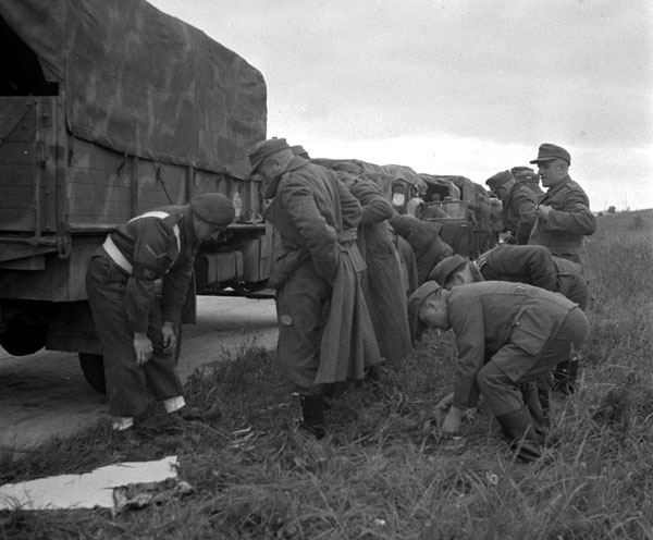 Lance-corporal J.G. Kallenberger searching a group of German prisoners before their return to occupied Germany